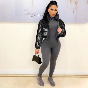 Detail view of black glossy puffer jacket and gray ribbed bodysuit on a fashion model