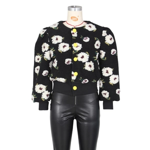 Detail of 3D floral embroidery, yellow buttons and puff sleeves on a black jacket