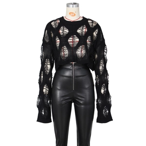 Detail of black hollowed-out knit crop top paired with high-waist faux leather pants
