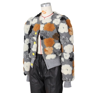 Detailed macro of floral patchwork faux fur jacket with vibrant yellow button accents