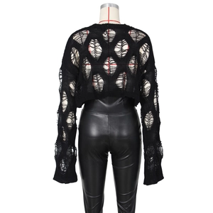 Detailed view of black hollow-out loose knit crop top and faux leather pants texture