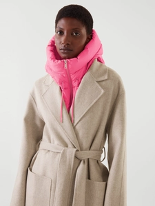 Détail d'un faux col à capuche matelassé rose porté avec un manteau en laine beige femme