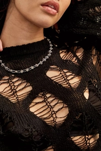 Close-up of silver knot link necklace over black hollow-out knit crochet top