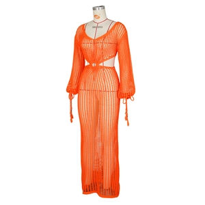 Détail de la robe au crochet orange avec découpe à la taille et finitions à pompons