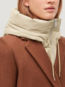 Détail d'un col à capuche amovible beige matelassé avec fermeture éclair argentée et cordon