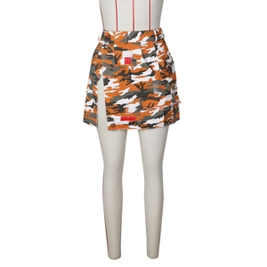 Détail de mini-jupe camouflage avec bords effilochés et braguette à boutons asymétrique