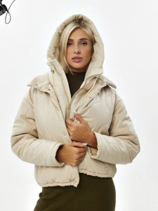 Détail d'un gilet beige matelassé à capuche avec motif ondulé et texture cuir mat