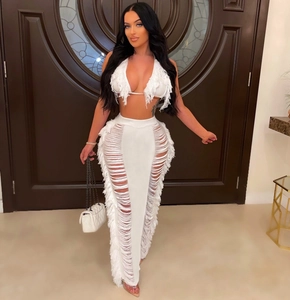 Detail of white crochet fringe two-piece set featuring halter top and high waist cutout skirt