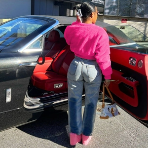 Outdoor close-up of premium rose pink faux fur jacket paired with light blue denim jeans