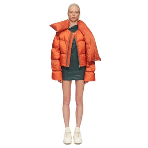 Chic orange cropped puffer jacket paired with dark green leather skirt and white sneakers