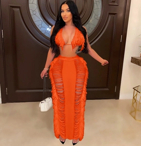 Detail of neon orange crochet knit two-piece set featuring long fringe and side cut-outs