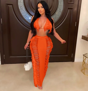 Detail of orange knitted two-piece set featuring tassel fringe and side hollow-out design