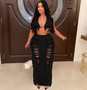 Detail of sexy black knit two-piece set with halter tassel top and side slit fringe skirt