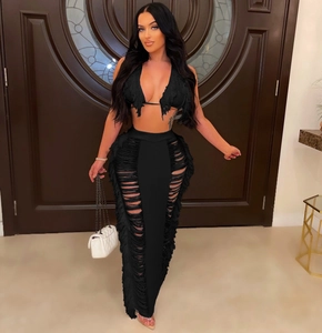 Detail of black knit two-piece set featuring tassel fringe trim and cutout maxi skirt