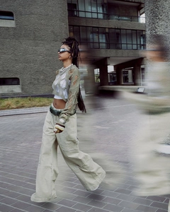 Close-up of olive green distressed knit top with cut-outs and beige cargo pants details