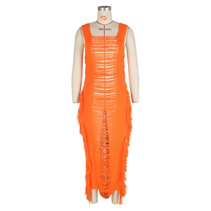 Détail d'une robe de plage en tricot ajouré orange avec des pompons à franges et un col carré