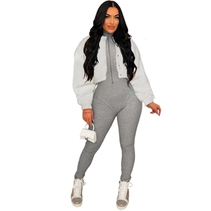 Detail view of a white faux fur jacket paired with a grey ribbed jumpsuit and white sneakers
