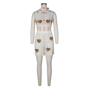 Dettaglio di un set a due pezzi in maglia bianca con ricami a cuore e texture traforata