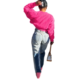Back view of a cropped fluffy pink faux fur jacket paired with light blue denim jeans