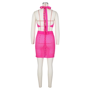 Dettaglio di top corto e minigonna in maglia rosso rosa con trame traforate rifinite
