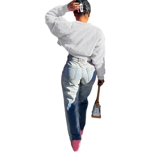Detail view of white faux fur short jacket and light blue straight jeans on a female model