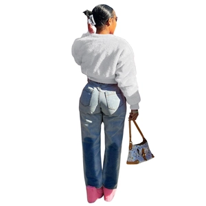 Back view of a white faux rabbit fur short jacket paired with blue denim jeans