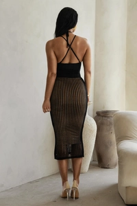 Dettaglio dell'abito nero a lupetto con spalline incrociate sulla schiena e gonna in maglia