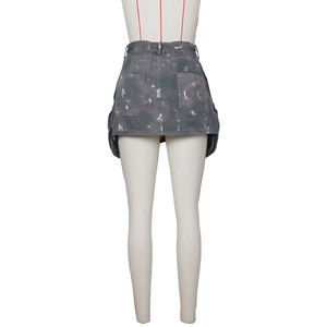 Détail de la jupe cargo en denim gris foncé avec taches de peinture blanche et grandes poches