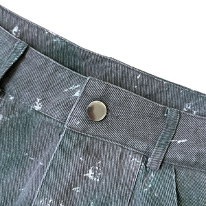 Détail de la taille d'une jupe cargo camouflage avec bouton métal et motifs d'éclaboussures