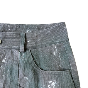 Détail du denim gris vintage avec lavage accentué et éclaboussures de peinture blanche