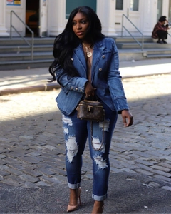 Detail of a denim blazer with lion-embossed gold buttons and distressed ripped jeans