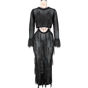Detail of black crochet maxi dress featuring intricate hollow-out knit and dense fringe trim