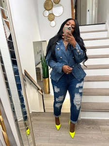 Close-up of slim-fit double-breasted denim blazer with golden buttons and ripped jeans