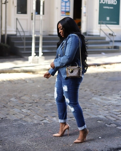 Detail of double-breasted denim blazer with lion buttons and ripped jeans on street