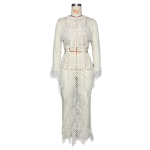 Detail of white crochet knit dress featuring delicate feather fringe and hollow waist cutout