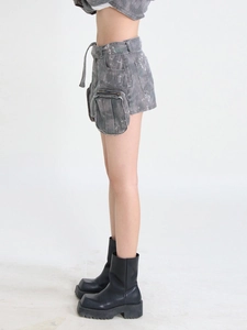 Détail de la texture denim gris avec taches d'encre, poche cargo et fermeture éclair