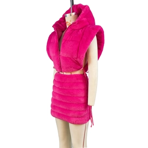 Dettaglio del set gilet corto in pelliccia sintetica rosa neon con cappuccio e minigonna