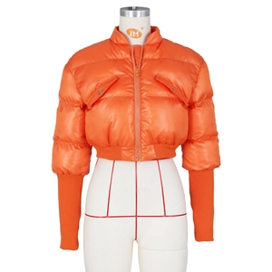 Detail of orange puffer jacket featuring large flap pockets and long ribbed knit cuffs