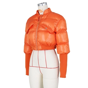 Detail view of bright orange shiny padded jacket with extra-long ribbed cuffs and stand collar
