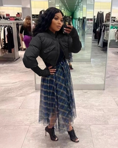 Detail of short black puffer jacket with stand collar and blue-green plaid mesh skirt