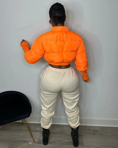 Rear view of bright orange short puffer jacket with high collar and beige jogger pants