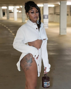 Detail of white faux shearling crop top and high slit skirt with button accents