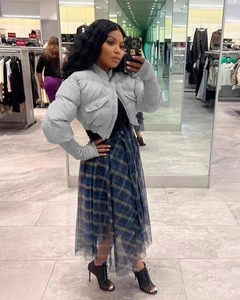 Detail of short grey puffer jacket with stand collar and plaid pleated midi skirt