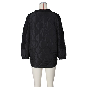 Detail of wave-quilted nylon fabric and knit cable sleeves on a black loose cotton jacket