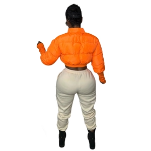 Rear view of women's bright orange cropped puffer jacket and off-white joggers set