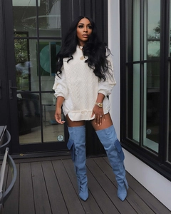 Detail shot of white oversized cable-knit sweater paired with light blue denim cargo boots