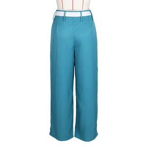 Dettaglio di pantaloni blu a gamba larga con vita alta, cintura bianca e tessuto fluido