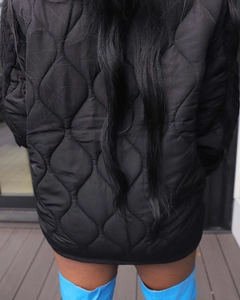 Back view of a black quilted jacket for women with stylish wave patterns and blue boots