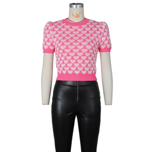 Close-up of pink knit short sleeve top with white heart patterns and black leather pants