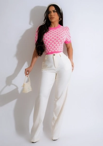 Pink short-sleeve knit top with white heart patterns and white wide-leg trousers